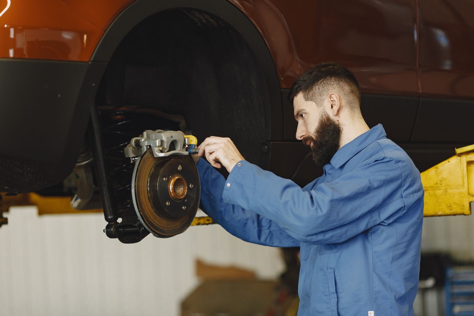 Mechanic replacing a car's brake caliper and rotor
